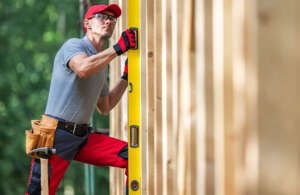 Construction Worker with Bubble Spirit Level Checking on Vertical Wooden Skeleton Frame Levels